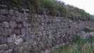 The unrestored portion is full of small holes and small trees sticking out from between the rocks.